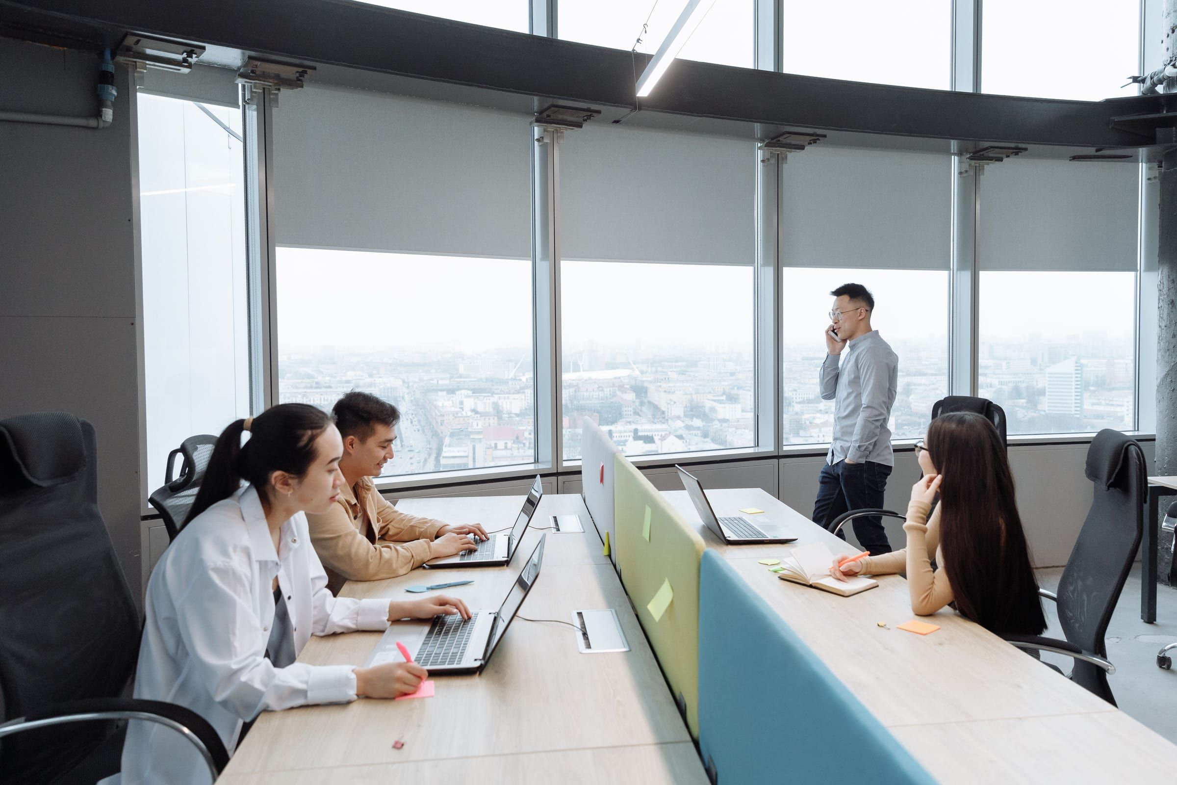 Employees working at shared desks in a high-rise office overlooking the city